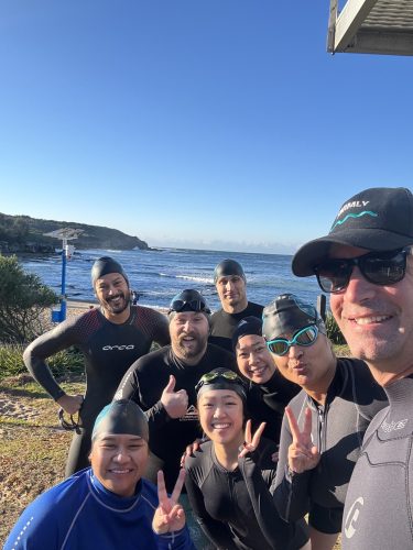Swimly coach and swimmer discussing stroke correction during an ocean swim session.
