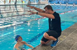 ason Cram mentoring a young swimmer poolside in Sydney