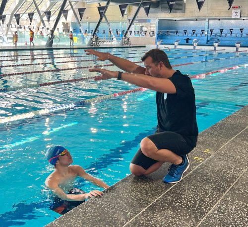 Teen swimmer getting feedback before race at Swimly ason Cram mentoring a young swimmer poolside in Sydney
